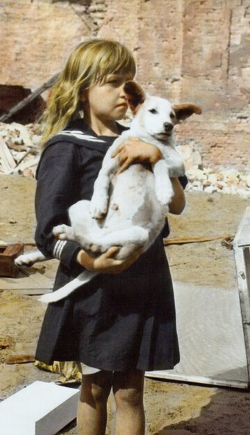 Żelazna 8 Dziewczynka z psem przy Żelaznej 8, w tle gruzy budynków zniszczonych w nalotach. Koloryzowana fotografia Juliena Bryana.