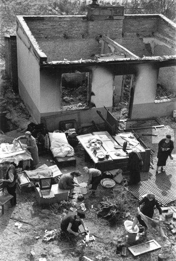 Skutki niemieckich bombardowań Rodzina przed swoim zniszczonym domem próbuje wykonywać zwyczajne, codzienne czynności. Fotografia Juliena Bryana.