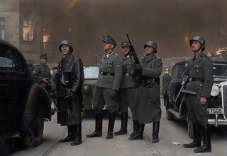 Jürgen Stroop (pośrodku, w czapce polowej) w płonącym getcie warszawskim, 1943 rok, zdjęcie koloryzowane