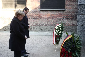 Kanclerz Niemiec Angela Merkel (L) oraz premier Mateusz Morawiecki (P) składają kwiaty przy Ścianie Straceń na terenie byłego niemieckiego nazistowskiego obozu zagłady Auschwitz. 