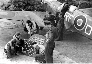 Lotnicy polskiego dywizjonu myśliwskiego 303 oglądają szczątki zestrzelonego samolotu niemieckiego "Ju 88". Z&nbsp;prawej widoczny samolot "Spitfire" należący do&nbsp;pilota Jana Zumbacha