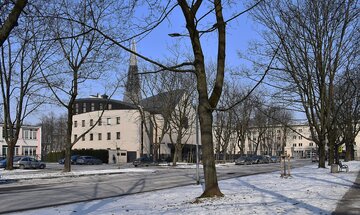 Kości&oacute;ł pw. Najświętszego Serca Pana Jezusa. Krak&oacute;w, Nowa Huta. Po&nbsp;lewej stronie widoczna szkoła, obok kościoła znajduje się krzyż