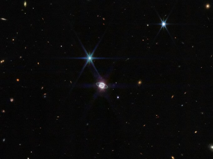 Zdjęcie wykonane przez Kosmiczny Teleskop Jamesa Webba (w bliskiej podczerwieni -&nbsp;NIRCam) w&nbsp;szerokim polu widzenia, pośrodku układ Neptuna z&nbsp;widocznymi pierścieniami