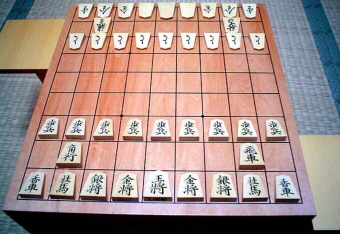 Plansza do gry Shogi; figury z przodu są ustawione jako stan początkowy, te w głębi są odwrócone
