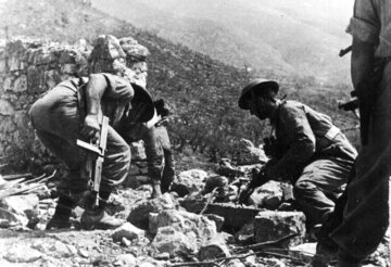 Polscy żołnierze, uzbrojeni w pistolety maszynowe Thompson M1 nad bunkrem, w którym znajdują się Niemcy, 25 maja 1944 r. 