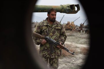 An Afghan national army soldier stands beside a Soviet-era tank on the 28th anniversary of Soviet-Afghan war