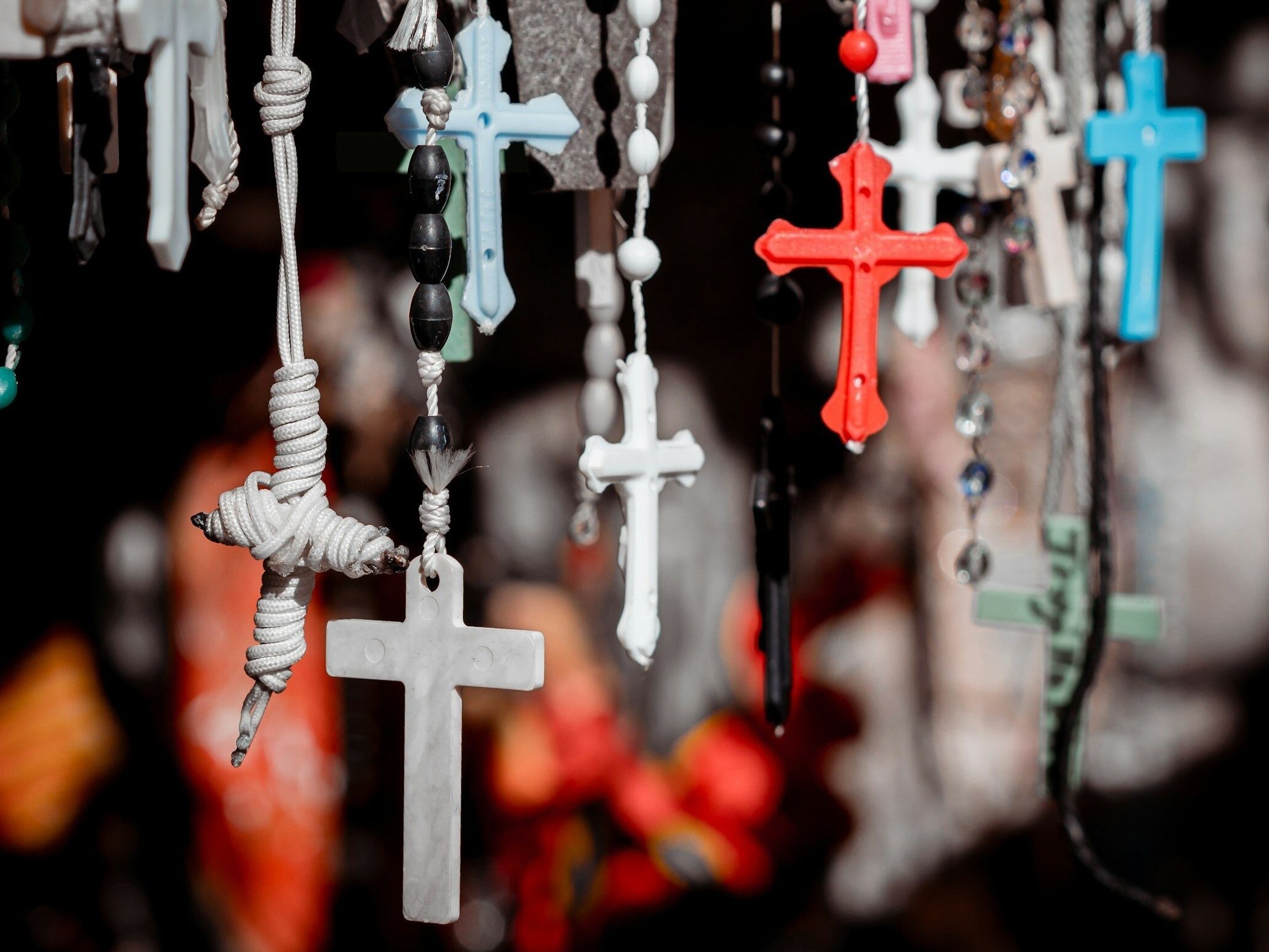 white and red cross hanging on black string