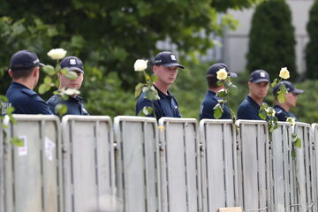 Barierki z zatkniętymi białymi różami i policjanci przed Sejmem