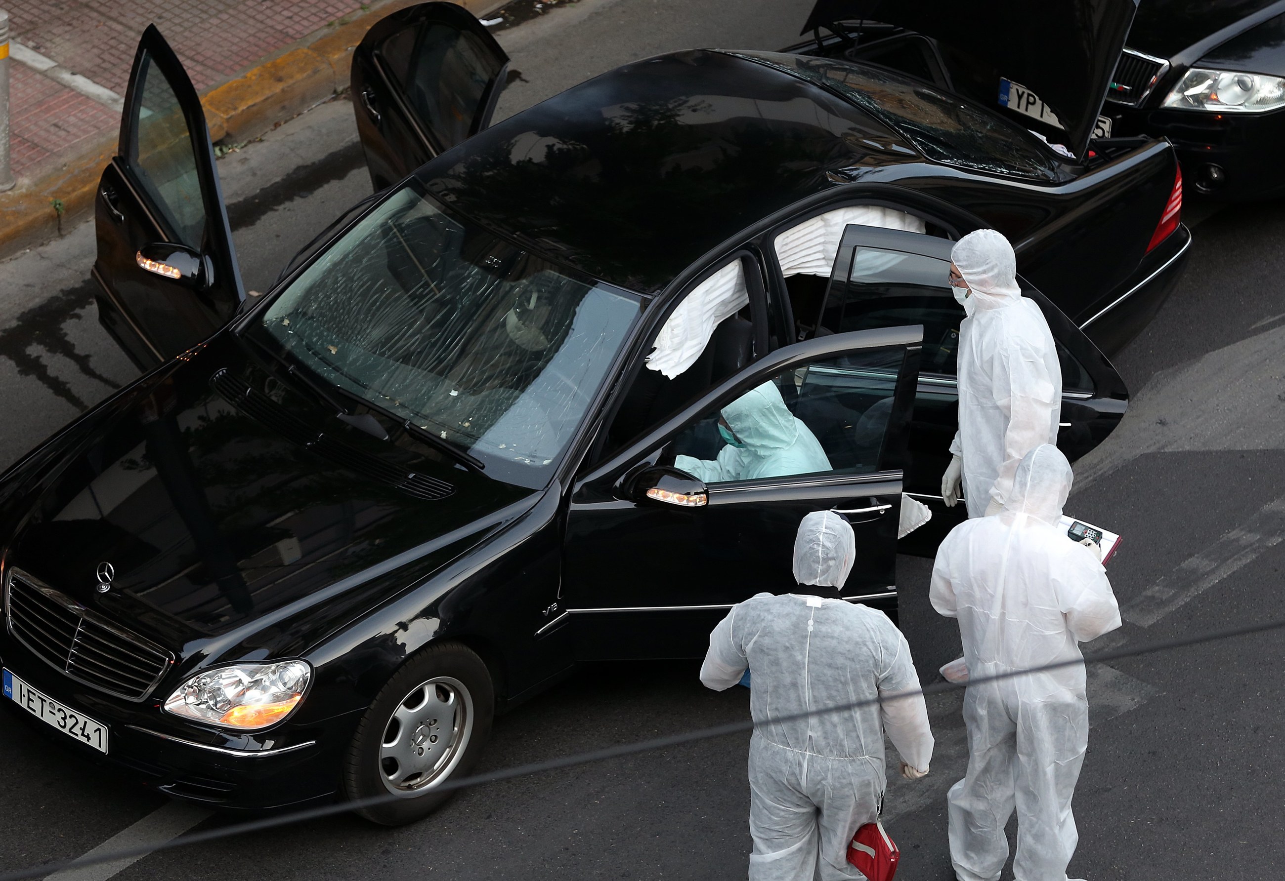 Policyjni śledczy przeprowadzają inspekcję samochodu byłego premiera Grecji Lukasa Papademosa po eksplozji spowodowanej ładunkiem wybuchowym