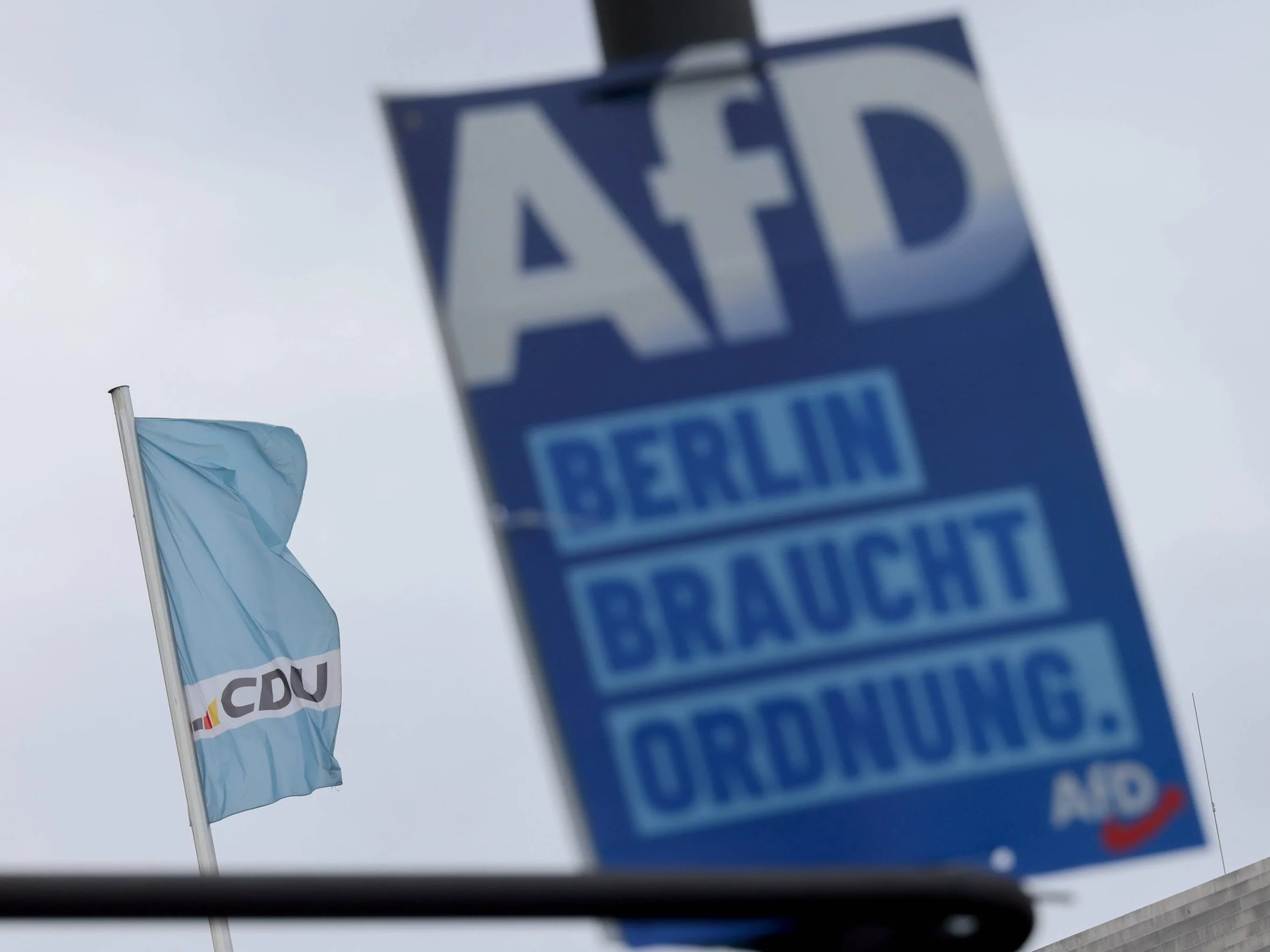 Logo AfD, w tle flaga CDU