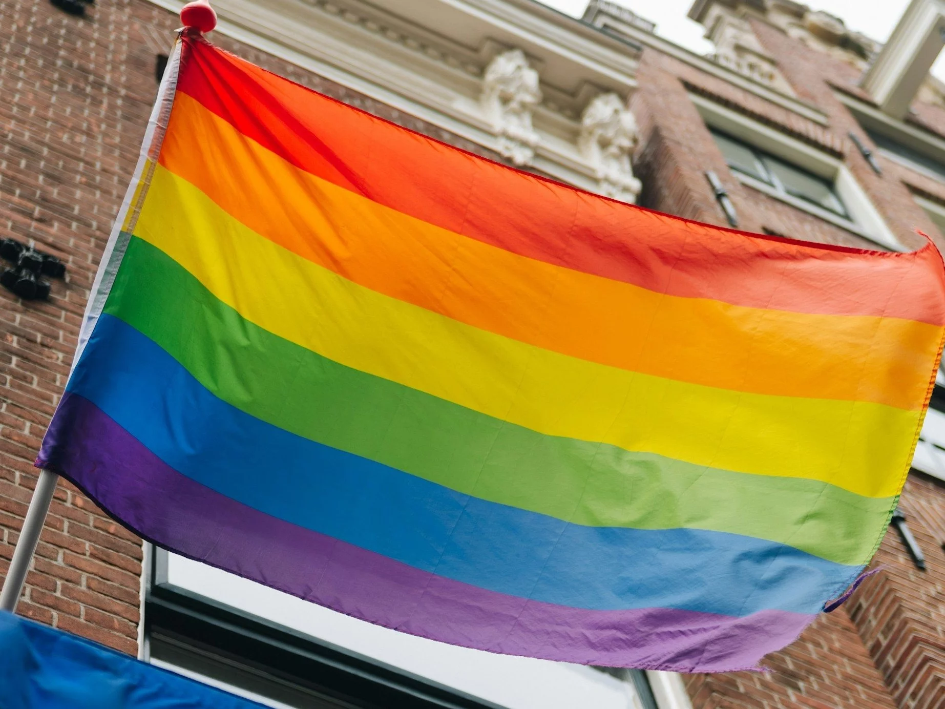 Pride month rainbow pride parade flag on flagpole. Equal rights, LGBTQ+ pride month for gay, lesbian, bisexual, transgender equality