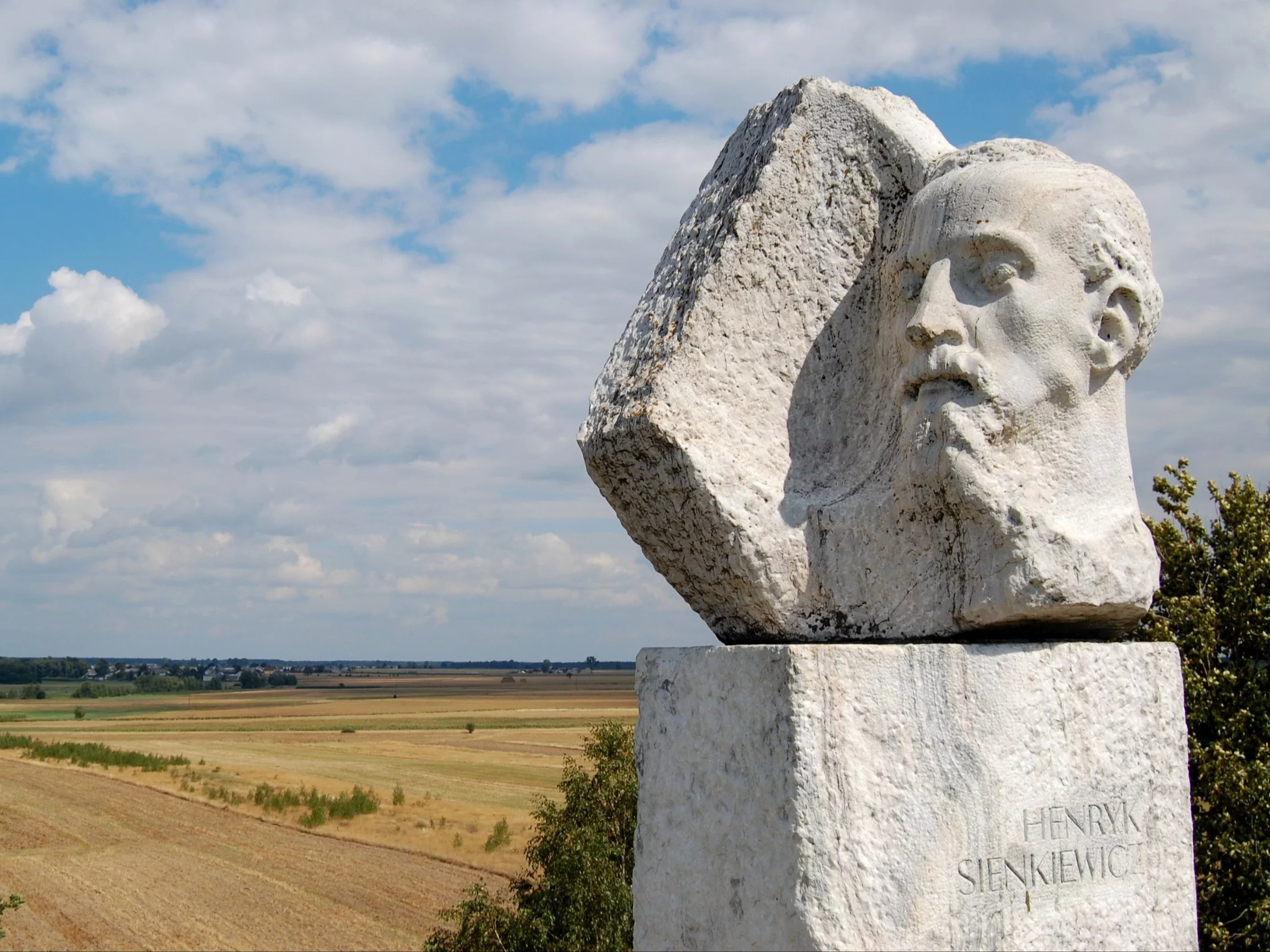 Pomnik Henryka Sienkiewicza na szczycie kopca jego imienia w Okrzei, w głębi widoczna Wola Okrzejska
