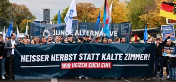 Demonstracja przeciwko inflacji. Protestujący trzymają transparent z napisem "Gorąca jesień zamiast zimnych pomieszczeń! Ogrzejemy cię!" Berlin. Październik 2022 r