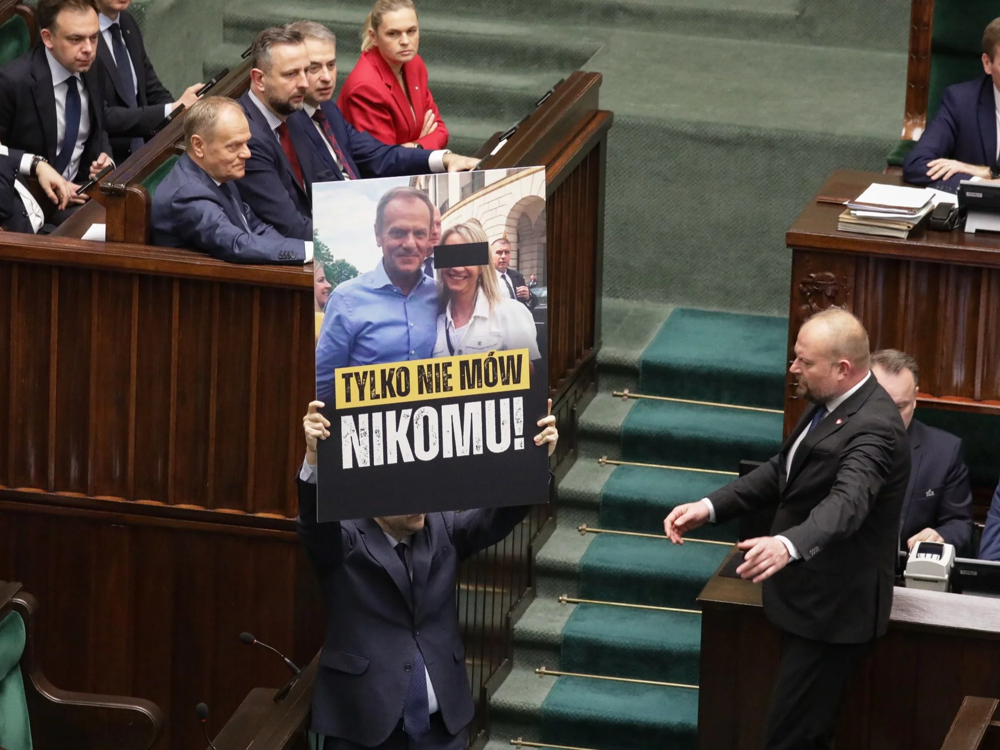 Posłowie prezentują baner na sali plenarnej