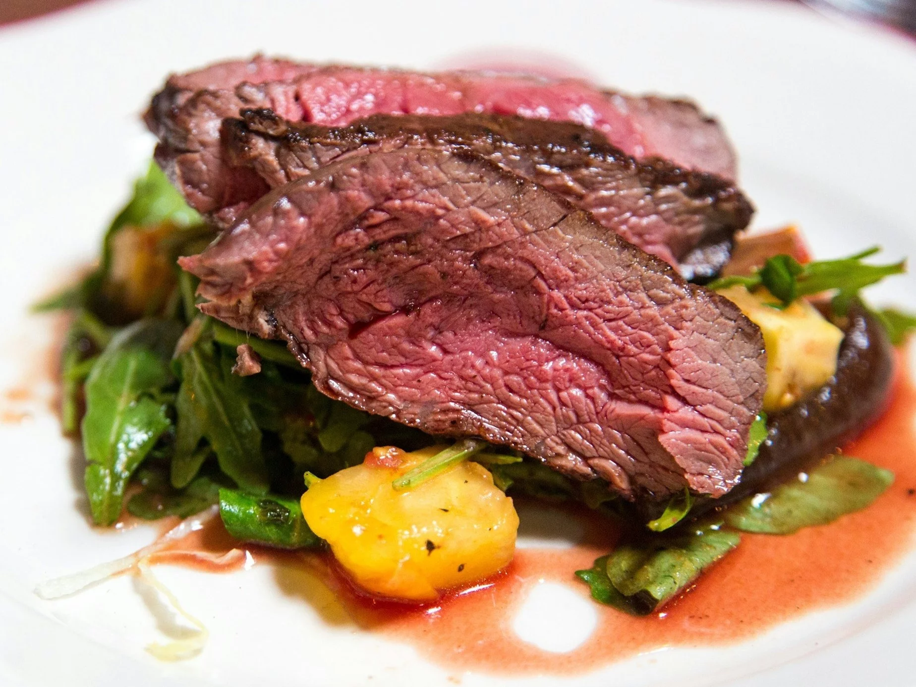 medium rare sliced steak in white ceramic plate