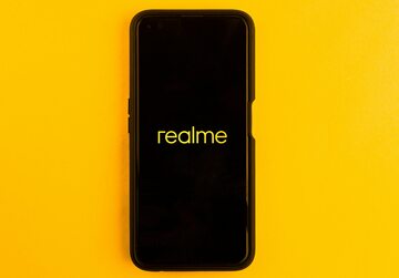 In this photo illustration the Realme logo seen displayed on a smartphone and on the background