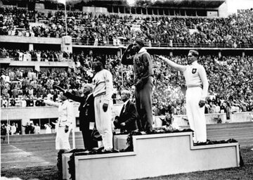 Jesse Owens na podium po wygraniu konkursu skoku w dal na Letnich Igrzyskach Olimpijskich 1936 roku w Berlinie