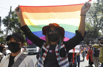 Kobieta trzymająca tęczową flagę, symbolizująca środowiska LGBT
