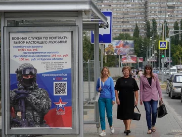 Kobiety przechodzą obok plakatu propagandowego w Kursku