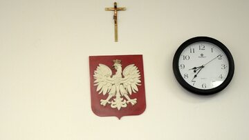 Krzyż, godło Polski, i zegar w klasie szkolnej. Zdjęcie ilustracyjne