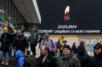 Ludzie przechodzą obok cyfrowego billboardu przedstawiającego płonącą świecę i hasło: "Petersburg opłakuje kraj"