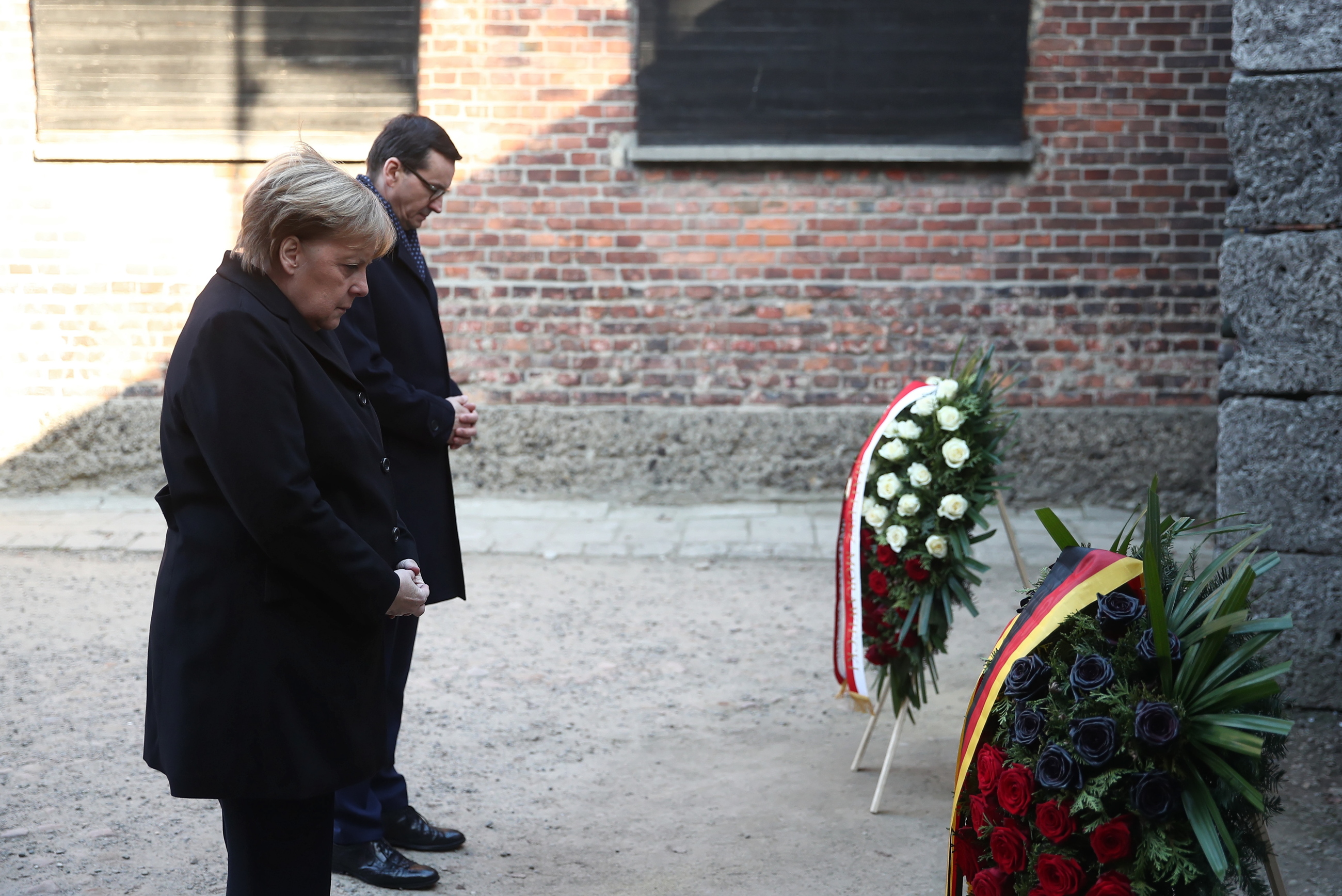 Kanclerz Niemiec Angela Merkel (L) oraz premier Mateusz Morawiecki (P) składają kwiaty przy Ścianie Straceń na terenie byłego niemieckiego nazistowskiego obozu zagłady Auschwitz.