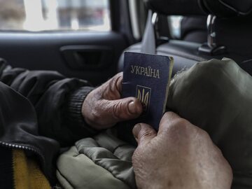 Mężczyzna trzymający w rękach ukraiński paszport.