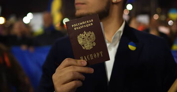 Mężczyzna trzymający w ręku rosyjski paszport, podczas protestu przeciwko działaniom Moskwy.