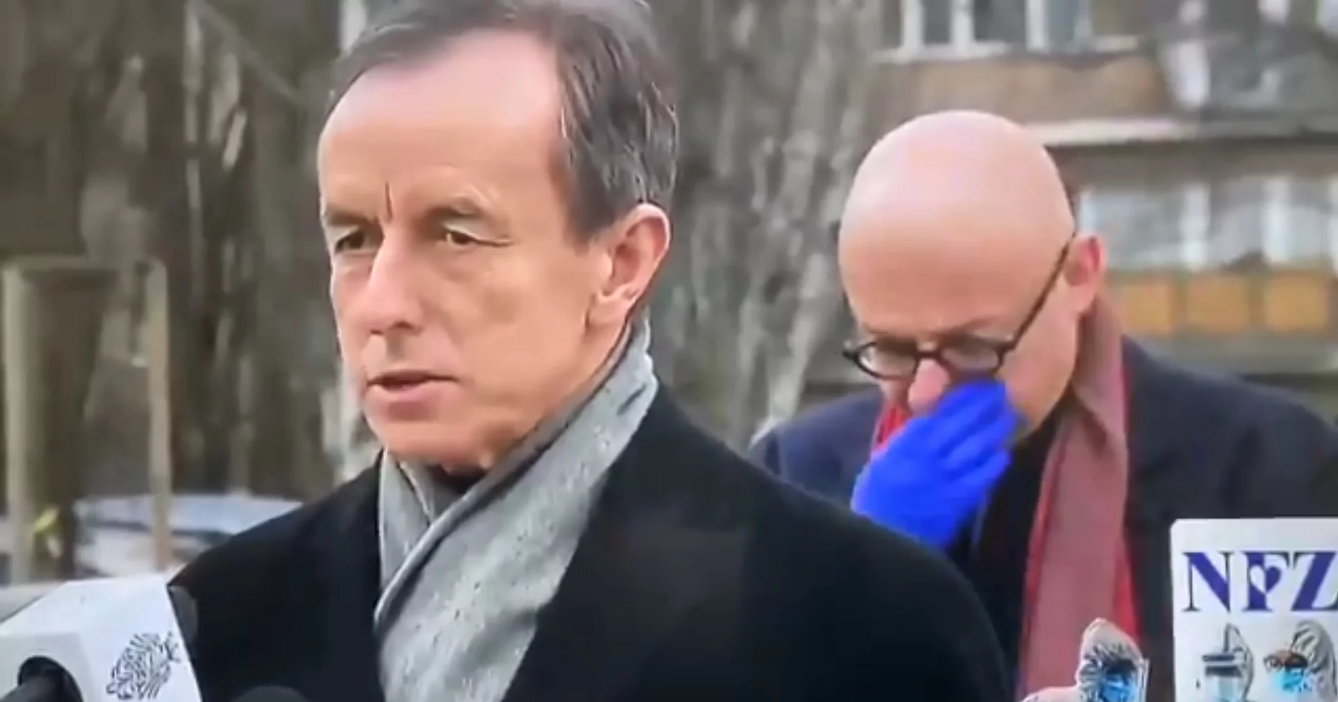 Michał Kamiński w rękawiczkach wyciera nos i usta