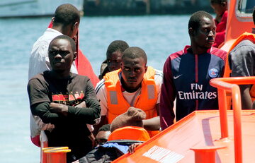 Migranci na łodzi w hiszpańskim porcie