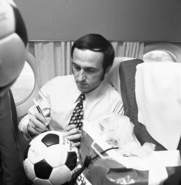 Powrót piłkarzy reprezentacji Polski po remisie z Anglią w 1973 r. Jan Domarski składa autografy na piłkach