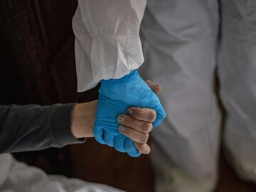 Pracownik służby zdrowia ubrany w ubrania ochronne pomaga chorej osobie, zdjęcie ilustracyjne