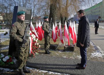 Premier Mateusz Morawiecki składa kwiaty przed tablicą poświęconą prezydentowi Lechowi Kaczyńskiemu w Piszu.