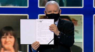Prezes PiS Jarosław Kaczyński trzyma podpisaną deklarację programową Zjednoczonej Prawicy
