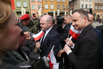 Prezydent Andrzej Duda rozdaje biało-czerwone flagi na Placu Zamkowym w Warszawie