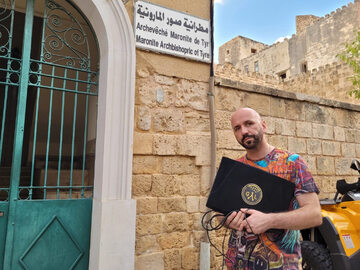 Robert Wyrostkiewicz przy kościele maronickim z komputerem z ładowarką zwróconymi przez Hezbollah