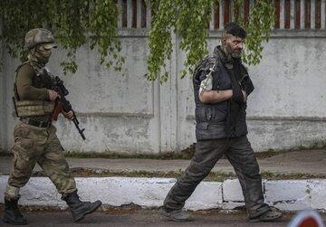 Rosyjski żołnierz eskortuje ukraińskiego żołnierza ewakuowanego z zakładów Azowstal w Mariupolu.