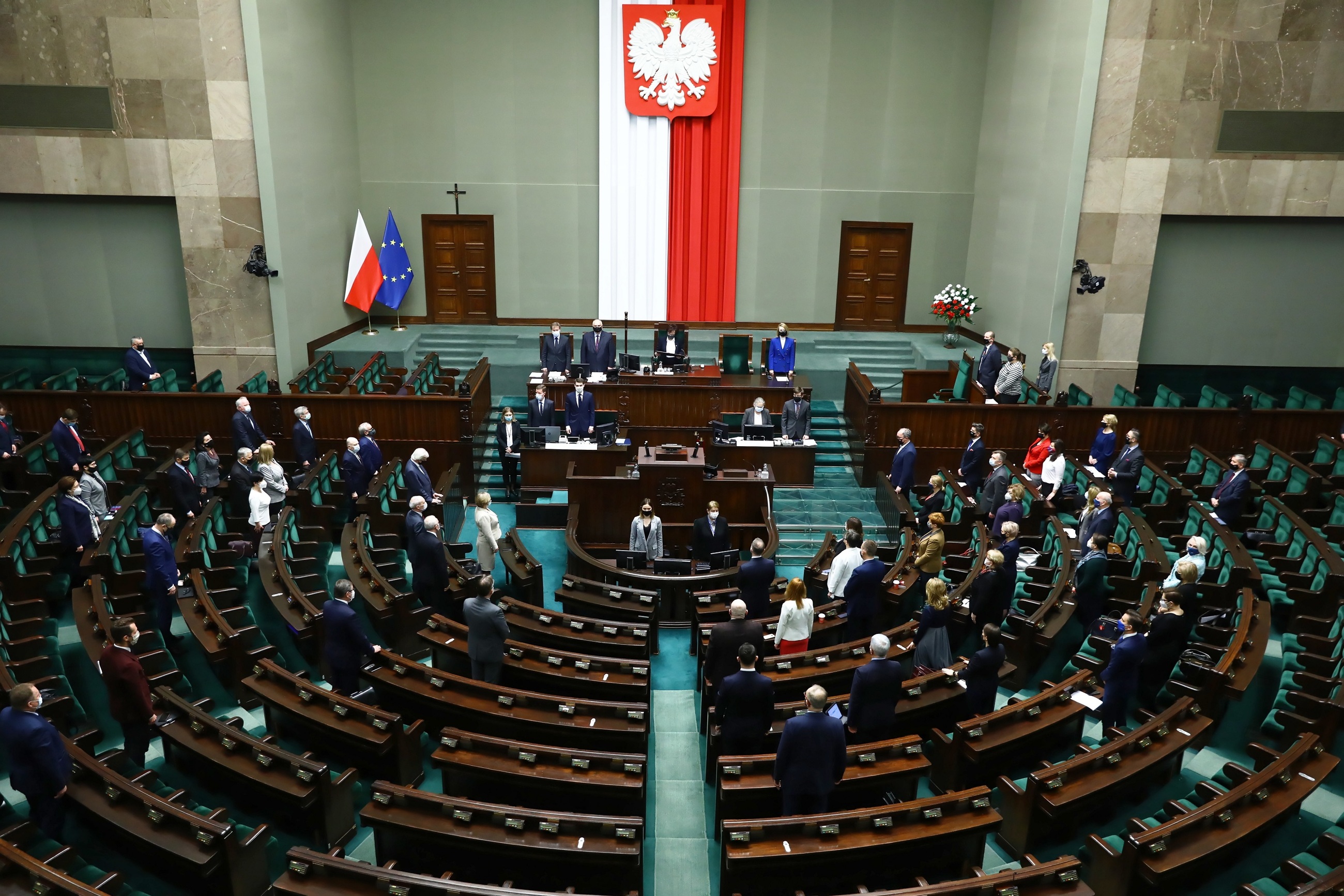 Posłowie na sali obrad, stoją w minucie ciszy dla Jana Lityńskiego.