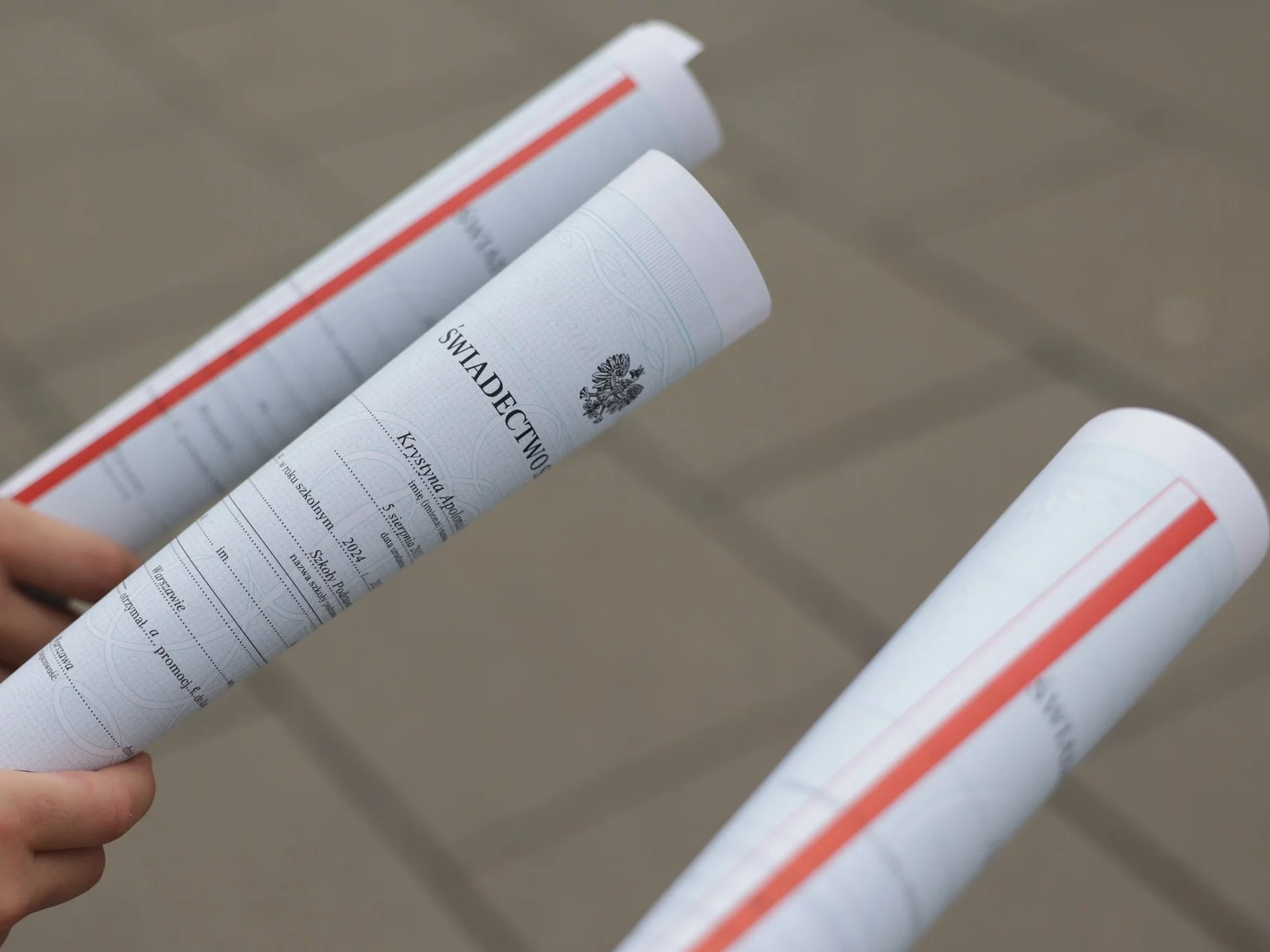 Uczniowie ze świadectwami z paskiem po zakończeniu roku szkolnego