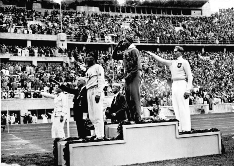 Jesse Owens na podium po wygraniu konkursu skoku w dal na Letnich Igrzyskach Olimpijskich 1936 roku w Berlinie