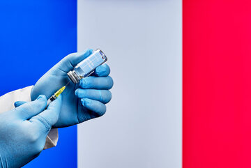 Szczepionka przeciw COVID-19 na tle francuskiej flagi, zdjęcie ilustracyjne
