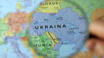 Ukraina widoczna przez szkło powiększające na tle mapy Europy. Zdj. ilustracyjne
