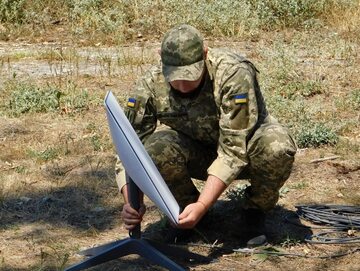 Ukraiński żołnierz instaluje system Starlink