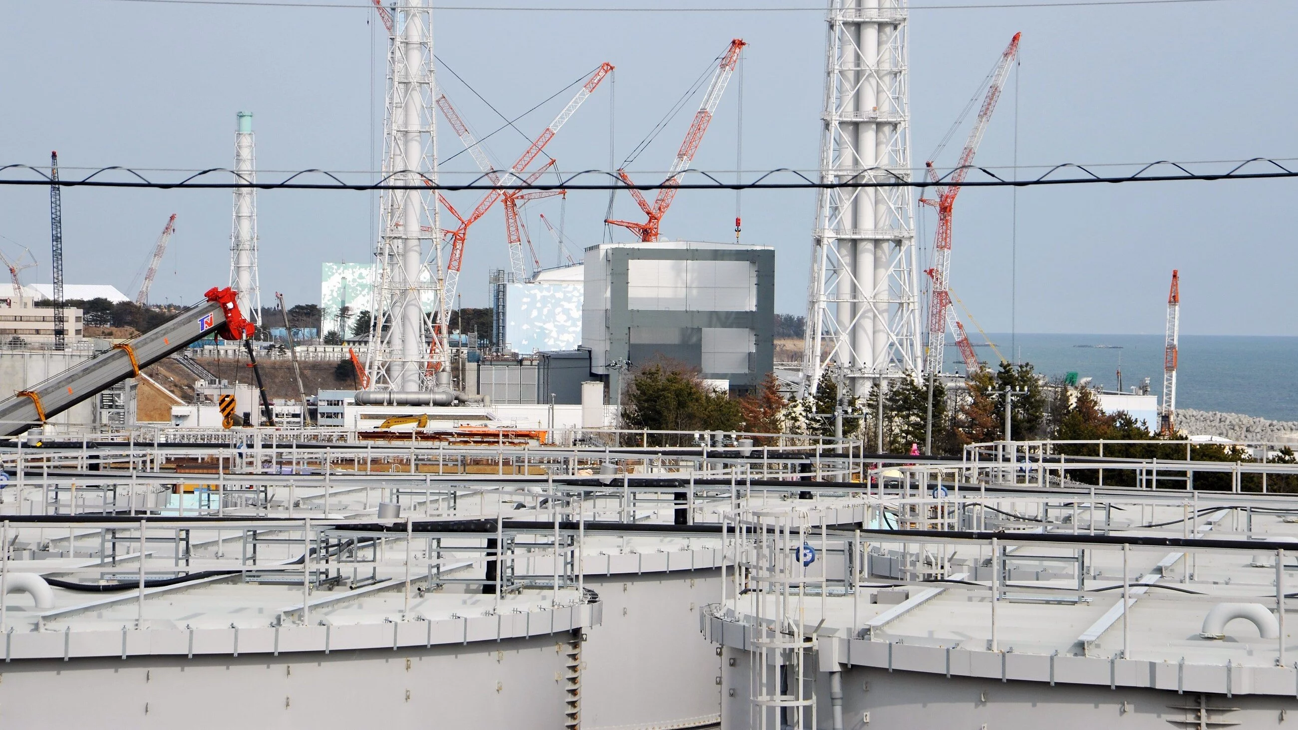 Zbiorniki zawierające zanieczyszczoną wodę przed budynkami reaktora w Fukushima Daiichi