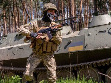 Wojna na Ukrainie. Żołnierz Gwardii Narodowej Ukrainy i transporter opancerzony MT-LB.