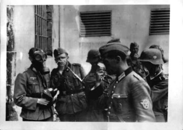 Żołnierze niemieccy z chusteczkami (jeden w masce przeciwgazowej) nad zwłokami ofiar NKWD we Lwowie